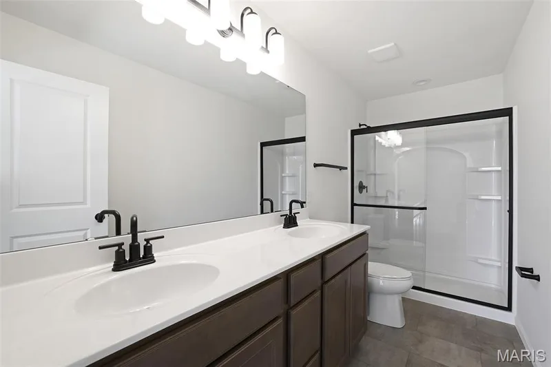 Full bath with a stall shower, double vanity, and dark tile patterned flooring — 19 Integrity Court, O'Fallon, MO 63385