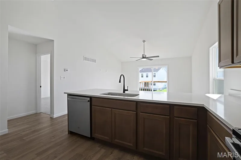 Kitchen featuring a peninsula, appliances with stainless steel finishes, dark wood finished floors, dark brown cabinetry, and ceiling fan — 19 Integrity Court, O'Fallon, MO 63385