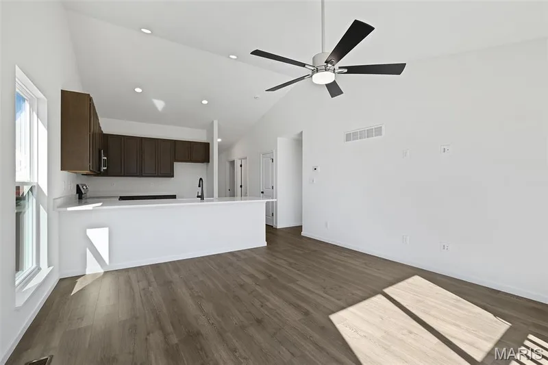 Unfurnished living room featuring high vaulted ceiling, dark wood-type flooring, recessed lighting, and ceiling fan — 19 Integrity Court, O'Fallon, MO 63385