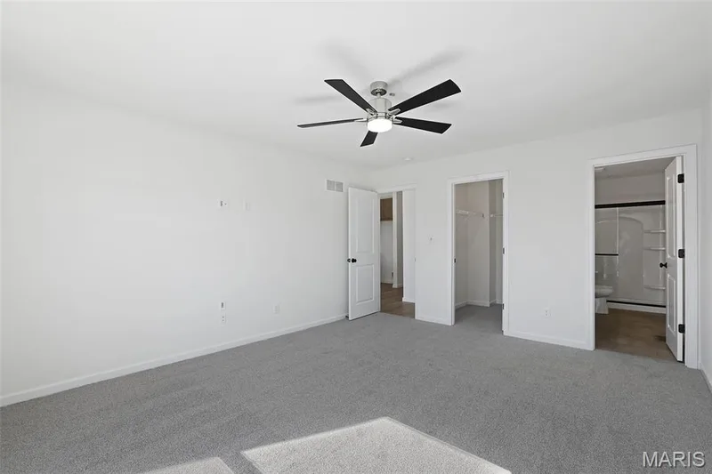 Unfurnished bedroom with a spacious closet, carpet, a ceiling fan, and connected bathroom — 19 Integrity Court, O'Fallon, MO 63385