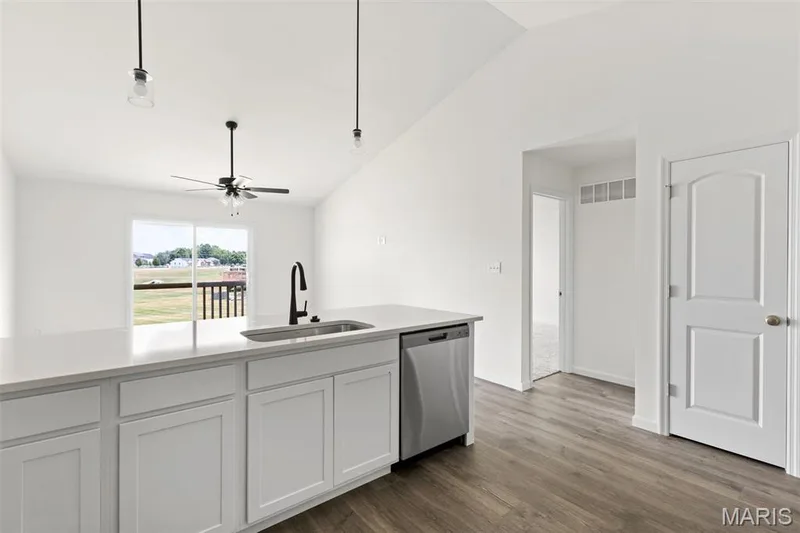 Kitchen featuring vaulted ceiling, white cabinets, dishwasher, dark wood finished floors, and a ceiling fan — 46 Integrity Court, O'Fallon, MO 63385