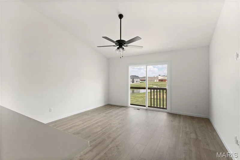 Spare room featuring light wood-style flooring, a water view, vaulted ceiling, and a ceiling fan — 46 Integrity Court, O'Fallon, MO 63385
