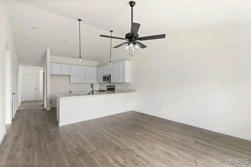 Kitchen with a peninsula, white cabinets, dark wood-style floors, light countertops, and high vaulted ceiling — 46 Integrity Court, O'Fallon, MO 63385