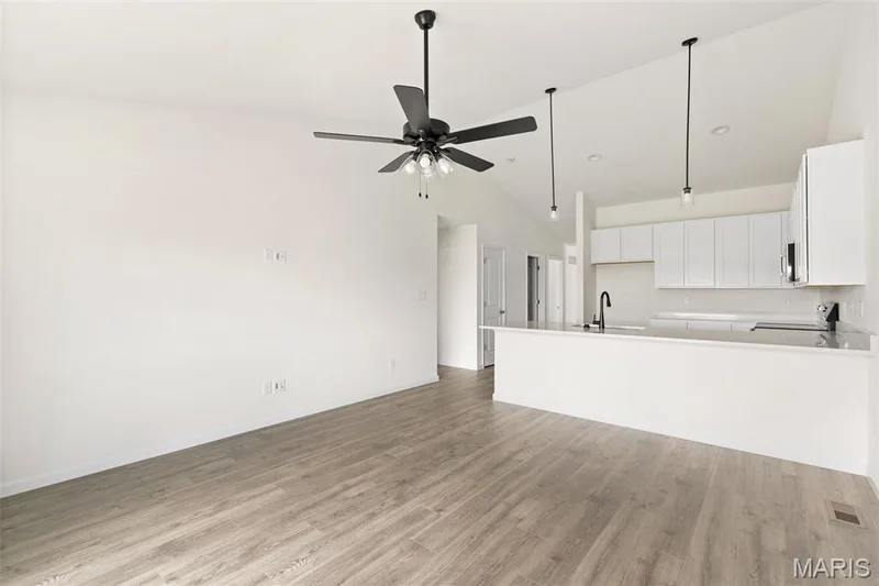 Unfurnished living room featuring light wood-style flooring, high vaulted ceiling, and a ceiling fan — 46 Integrity Court, O'Fallon, MO 63385