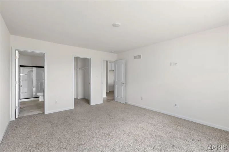 Unfurnished bedroom with a walk in closet, carpet, and ensuite bath — 46 Integrity Court, O'Fallon, MO 63385