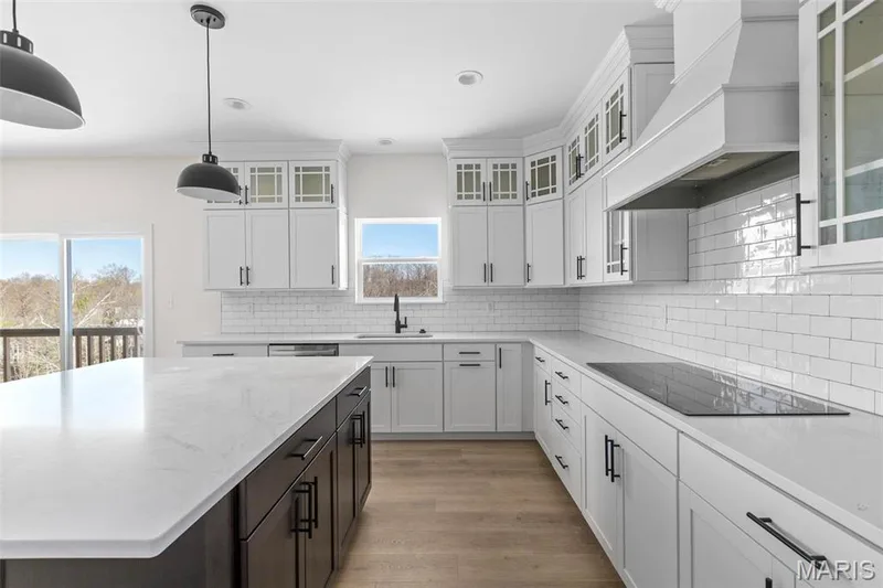Kitchen featuring white cabinetry, black electric cooktop, premium range hood, and a wealth of natural light — 3 Sequoia at Bluestem Estates, St Charles, MO 63367