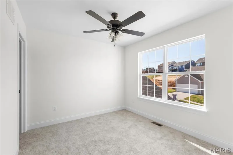 Empty room featuring light carpet, ceiling fan, and a healthy amount of sunlight — 3 Sequoia at Bluestem Estates, St Charles, MO 63367