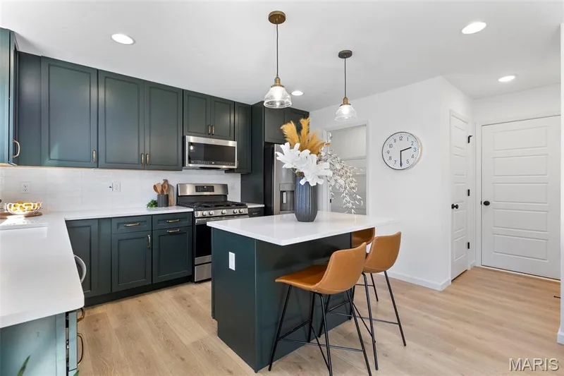 Kitchen with appliances with stainless steel finishes, a kitchen island, hanging light fixtures, light wood-style floors, and recessed lighting — 3 Sterling at Wilmer Crossing, Wentzville, MO 63385