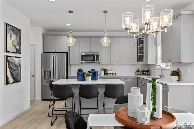 Kitchen with pendant lighting, gray cabinets, stainless steel appliances, light wood-type flooring, and sink — 3 Ashford at Elm Crossing, St Charles, MO 63301
