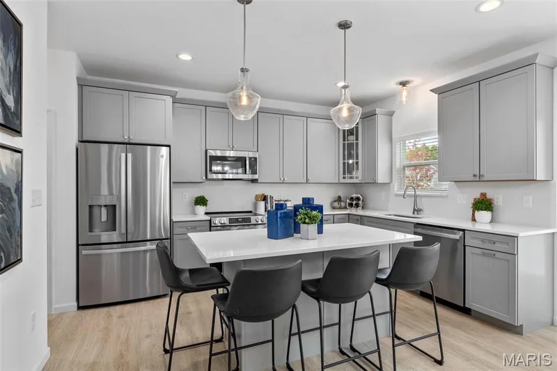 Kitchen featuring gray cabinets, sink, a kitchen island, appliances with stainless steel finishes, and decorative light fixtures — 3 Ashford at Elm Crossing, St Charles, MO 63301
