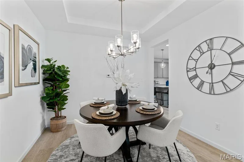 Dining room with light hardwood / wood-style floors, a tray ceiling, and a chandelier — 3 Ashford at Elm Crossing, St Charles, MO 63301