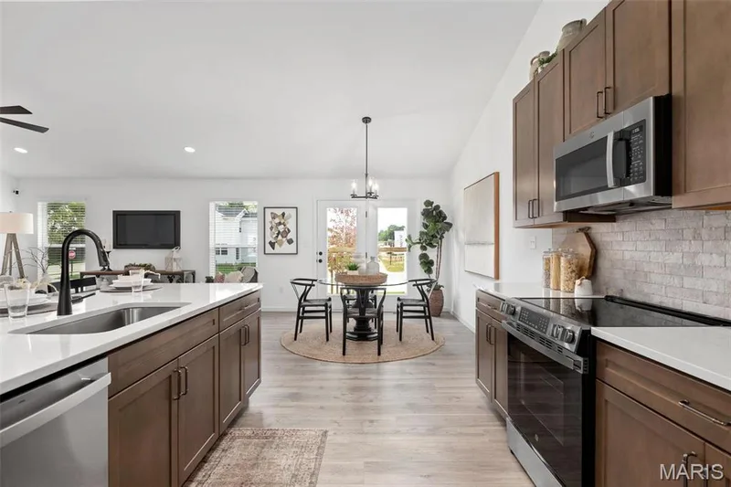 Kitchen with light hardwood / wood-style floors, stainless steel appliances, plenty of natural light, and sink — 3 Aspen at Elm Crossing, St Charles, MO 63301
