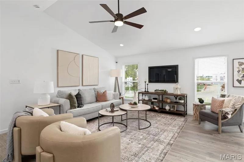 Living room with ceiling fan, light hardwood / wood-style flooring, vaulted ceiling, and a wealth of natural light — 3 Aspen at Elm Crossing, St Charles, MO 63301