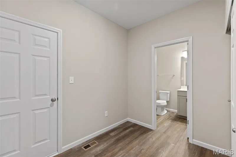 Unfurnished bedroom featuring dark wood-style floors and ensuite bath — 225 Windmill View Drive, O'Fallon, MO 63385