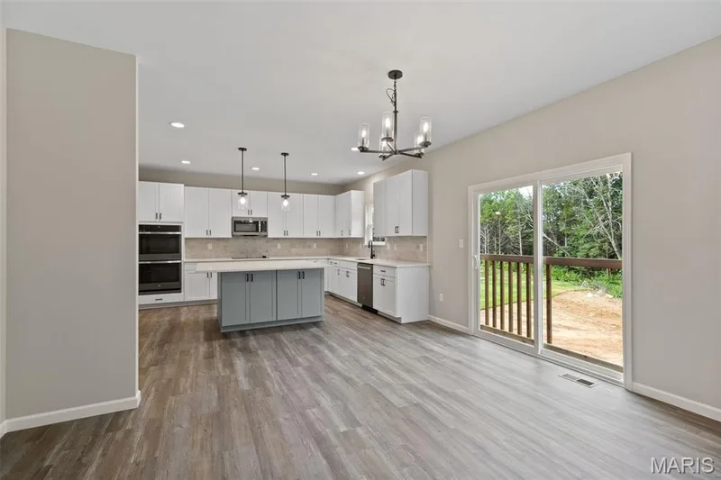 Kitchen with decorative light fixtures, a chandelier, white cabinets, appliances with stainless steel finishes, and light wood-style flooring — 225 Windmill View Drive, O'Fallon, MO 63385