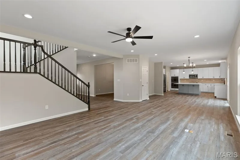Unfurnished living room with recessed lighting, ceiling fan, light wood-type flooring, stairway, and a chandelier — 225 Windmill View Drive, O'Fallon, MO 63385