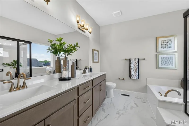 Primary Bathroom with view of tub and double wave bowl vanity — 421 Farmhouse Drive, O'Fallon, MO 63385