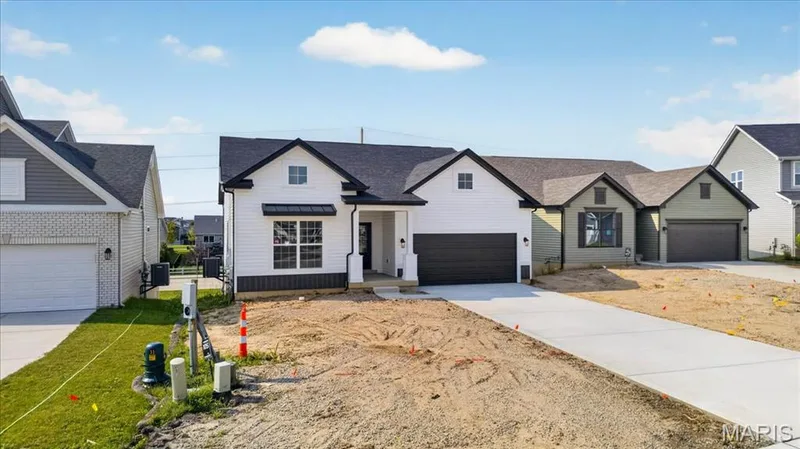 Designer-inspired from the moment you arrive, this home offers a sophisticated white exterior accented by black windows, metal roof detail, decorative gables, and professional landscaping potential. An inviting elevation that feels both elegant and welcoming. — 86 River Wind Drive, St Charles, MO 63301