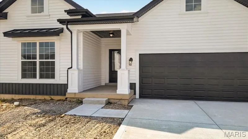 Stunning modern farmhouse elevation featuring white siding with black accents, decorative gables, covered front porch, and exceptional curb appeal. Timeless design meets today's style in this beautifully crafted home. — 86 River Wind Drive, St Charles, MO 63301