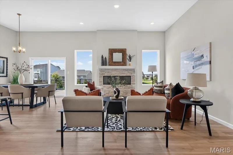 The spacious great room is the heart of the home, featuring soaring ceilings, expansive windows, a stunning mantle height stone fireplace, and an open layout that seamlessly connects to the dining area and covered deck. — 86 River Wind Drive, St Charles, MO 63301