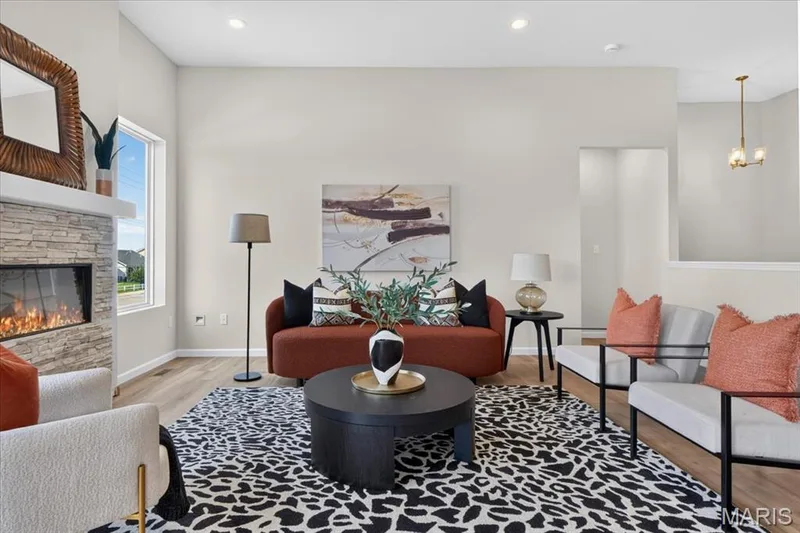 This stunning great room showcases 11' ceilings, recessed lighting, luxury vinyl plank flooring, and a contemporary stone fireplace. Large windows and direct access to the covered deck fill the space with natural light and enhance indoor-outdoor living. — 86 River Wind Drive, St Charles, MO 63301