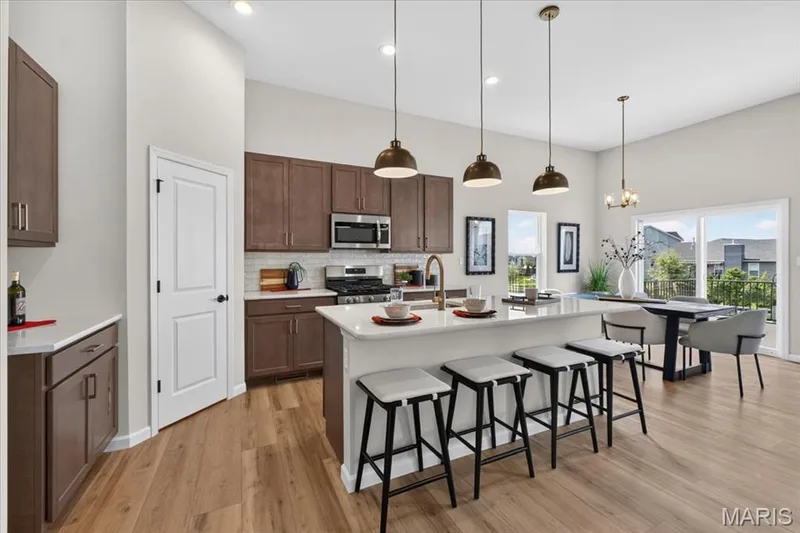 Designed for both everyday living and entertaining, the spacious kitchen offers a generous island, quartz countertops, stylish pendant lighting, stainless steel appliances, and a walk-in pantry for exceptional storage. — 86 River Wind Drive, St Charles, MO 63301