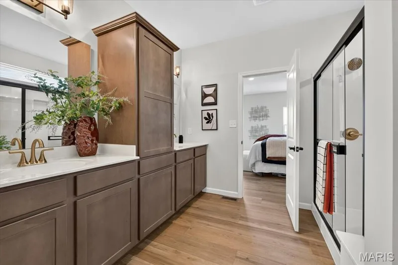 Designed as a private retreat, the spacious primary bath showcases dual sinks, abundant cabinet storage, a beautifully tiled walk-in shower with modern black-framed glass doors, and an adjoining walk-in closet that makes everyday living effortless. — 86 River Wind Drive, St Charles, MO 63301