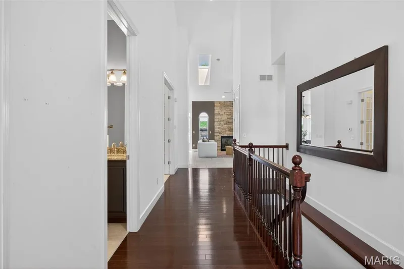 Entry foyer hallway featuring dark wood-finish flooring and a staircase with a matching wood banister — 216 Woodland Place Court, St Charles, MO 63303