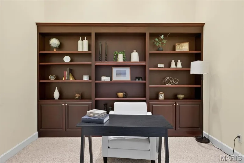 Home office with custom built-in shelving unit featuring multiple open shelves and lower cabinet storage — 216 Woodland Place Court, St Charles, MO 63303