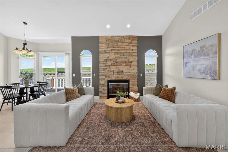 Great Room featuring a stone-clad fireplace with a dark accent wall, vaulted ceiling, recessed lighting, arched windows and a skylight. — 216 Woodland Place Court, St Charles, MO 63303