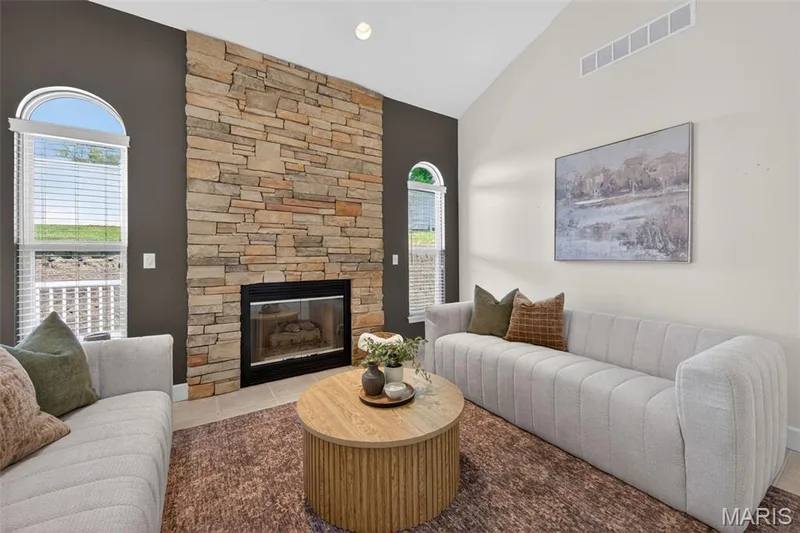 Living area featuring a floor-to-ceiling stacked stone fireplace with a black framed firebox — 216 Woodland Place Court, St Charles, MO 63303
