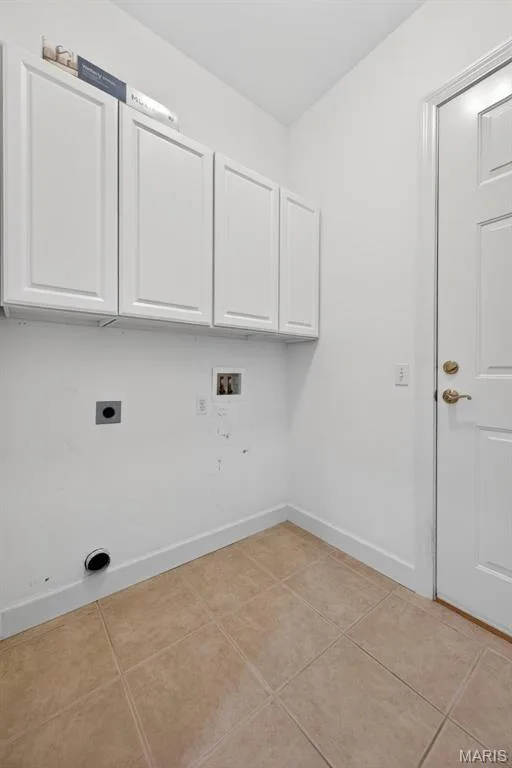 Main floor laundry room with tile flooring and four upper white cabinetry units — 216 Woodland Place Court, St Charles, MO 63303