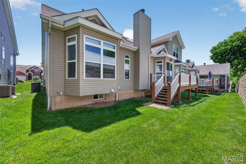 Rear exterior featuring a multi-level wood deck with white railings, a bay window, and tan siding — 216 Woodland Place Court, St Charles, MO 63303