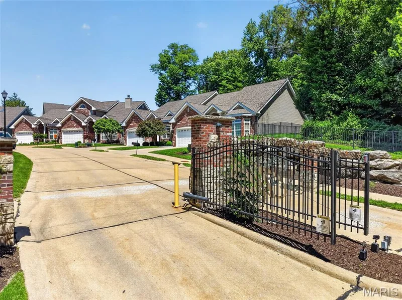 Gated community entrance featuring an automatic wrought iron gate and brick columns — 216 Woodland Place Court, St Charles, MO 63303