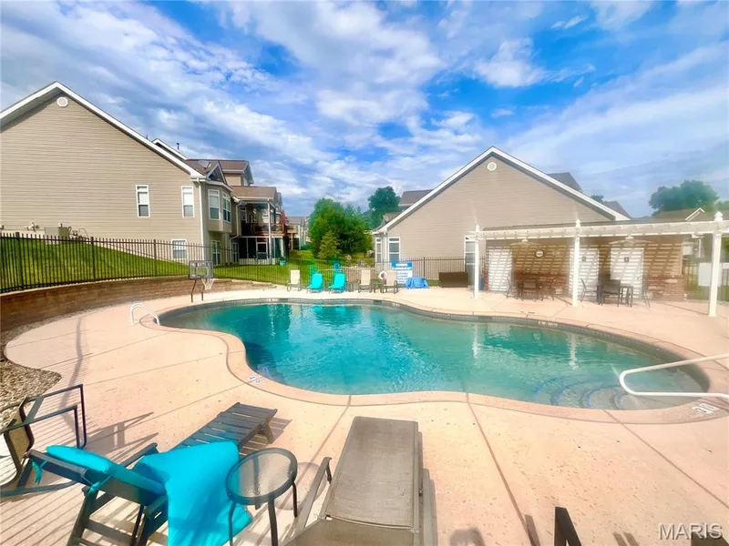 Freeform swimming pool with integrated steps, surrounded by a concrete patio — 197 Woodland Place Court, St Charles, MO 63303