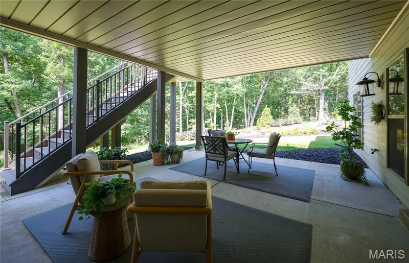 Covered concrete patio with Underdeck paneled ceiling and the pond in the backdrop — 150 Delcreek Estates Drive, Foristell, MO 63348