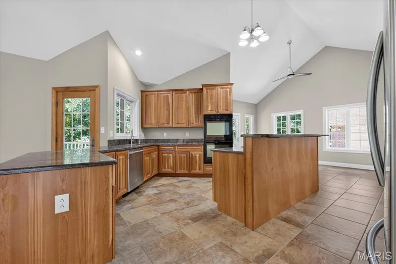Chef-inspired kitchen featuring rich wood cabinetry, granite countertops, and elegant tile floors! — 18517 Gredan Court, Wildwood, MO 63069