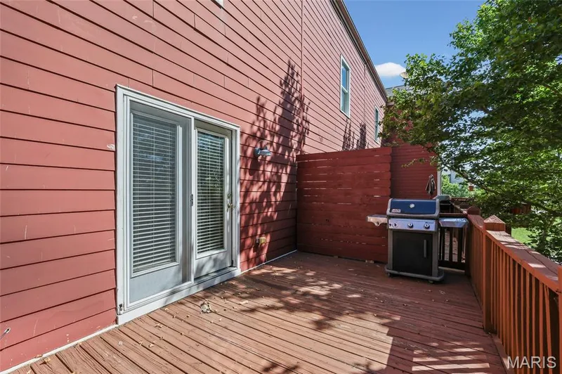 Exterior deck featuring wood flooring and railings, privacy wall, and sliding glass door — 3245 Domain Street, St Charles, MO 63301