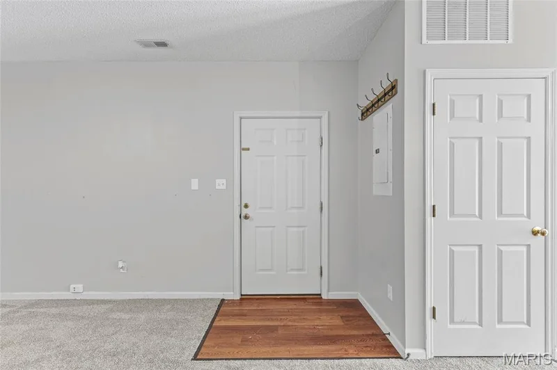 Hardwood-finish flooring entry area, wall-mounted coat rack, and white paneled doors — 3245 Domain Street, St Charles, MO 63301