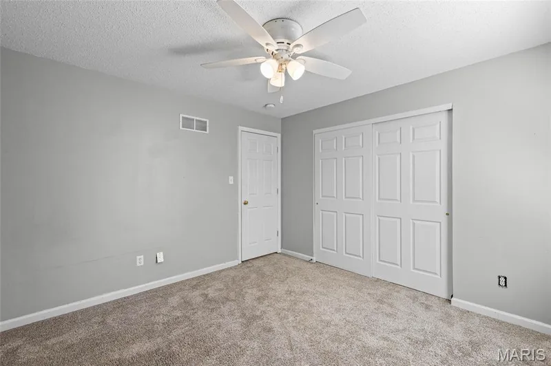 Carpeted flooring, white paneled closet doors, ceiling fan with integrated lighting, and neutral wall tones — 3245 Domain Street, St Charles, MO 63301