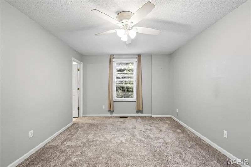 Light gray wall color, textured ceiling, ceiling fan with integrated lighting, window with blinds and drapes, and carpeted flooring — 3245 Domain Street, St Charles, MO 63301
