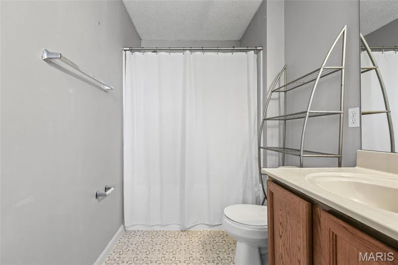 Bathroom featuring a vanity with wood-finish cabinetry, a built-in sink, and a large mirror — 3245 Domain Street, St Charles, MO 63301