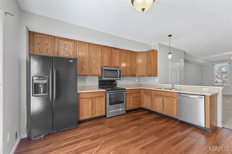 Kitchen featuring wood-finish flooring, oak cabinetry, stainless steel appliances, and a double basin sink — 3245 Domain Street, St Charles, MO 63301