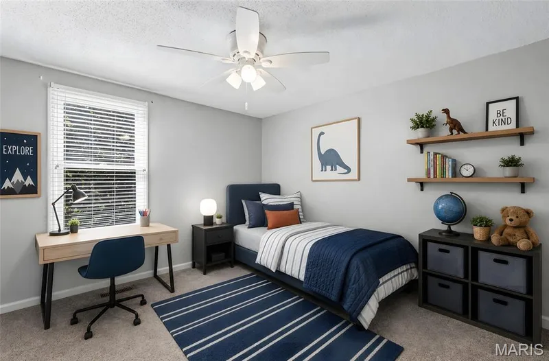 Single window with white blinds, neutral wall paint, ceiling fan with integrated lighting, wood-finish desk, and built-in shelving — 3245 Domain Street, St Charles, MO 63301