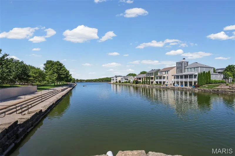 Waterfront property featuring a stone retaining wall, private balconies, and a manicured lawn — 3245 Domain Street, St Charles, MO 63301