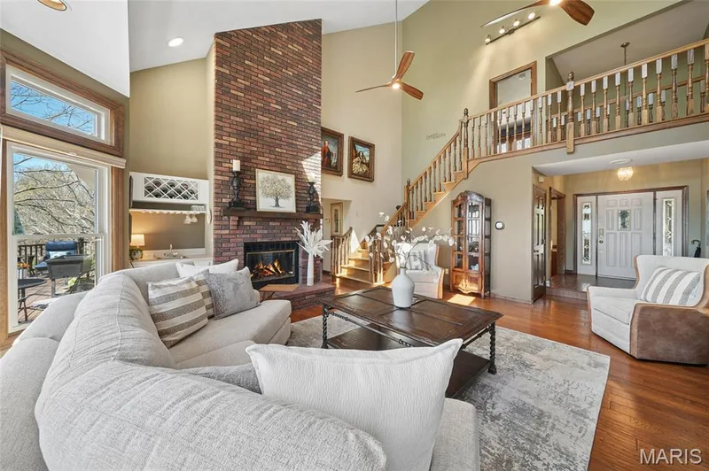 Living area featuring a ceiling fan, wood finished floors, a brick fireplace, and lofted ceiling — 1553 Ridge Road, Wildwood, MO 63021