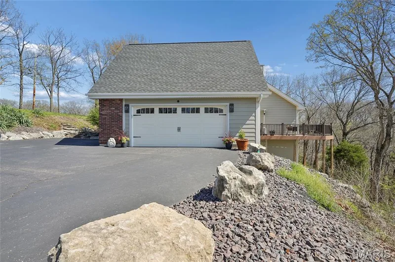 View of side of home with a garage, a shingled roof, brick siding, and asphalt driveway — 1553 Ridge Road, Wildwood, MO 63021