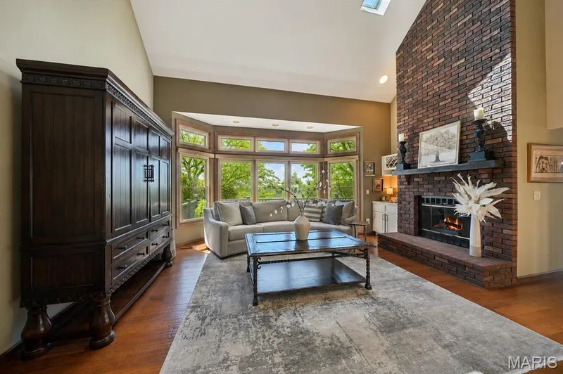 Vaulted ceiling with skylight, brick fireplace with mantel, hardwood flooring, and bay windows — 1553 Ridge Road, Wildwood, MO 63021
