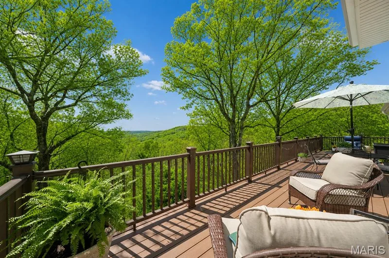 Expansive wood-finish deck with a brown railing system, overlooking a lush, wooded landscape — 1553 Ridge Road, Wildwood, MO 63021