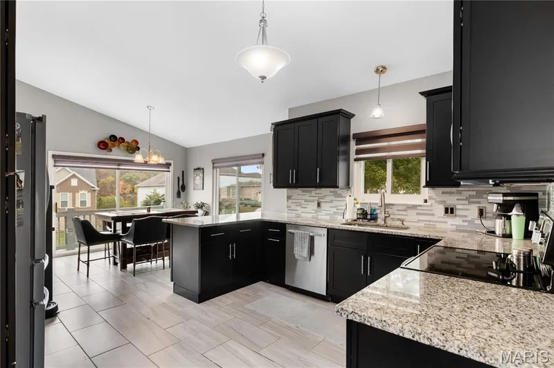 Kitchen with dark cabinets, decorative light fixtures, and vaulted ceiling — 10107 Greenbriar Court, Foristell, MO 63348